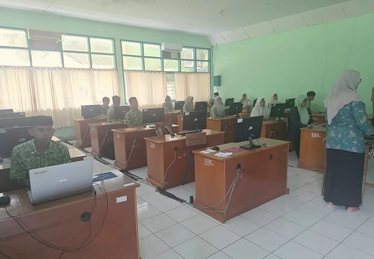 Santri MA berseragam batik hijau mengerjakan ujian di depan komputer di laboratorium